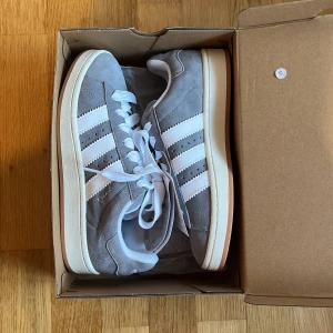 Adidas Campus 00s - Säljer dessa helt slutsålda Adidas Campus 00s i grå. Aldrig använda i orginalboxen med lappar på. Storlek 40 2/3, men skulle säga att de mer sitter som 39,5-40.  !Skorna finns fortfarande kvar, köp direkt för 1350 kr inklusive frakt!