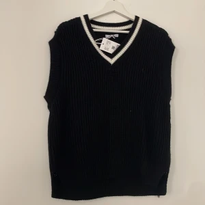 Stickad väst - En stickad svart väst med vit krage aldrig använd prislappen kvar