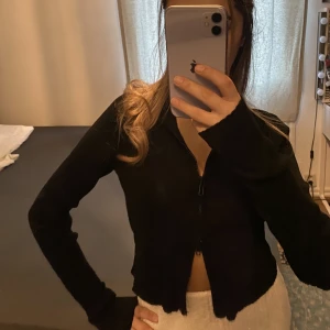 Justerbar tröja med dragkedja - En snygg svart tröja från Monki med två kedjor vid varsin ände av tröjan, går att justera tröjan till hur öppen eller stängd man föredrar. Skönt material och i bra skick, knappt använd!