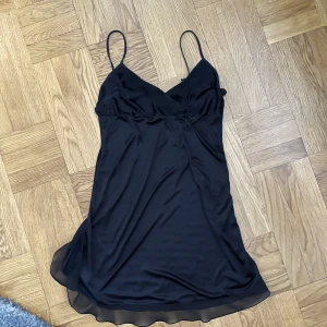 Svart nattlinne - Gulligt svart nattlinne med volang och rosett. Köpt second hand men i väldigt bra skick, har aldirg använt det själv. Står ingen storlek men passar S-M