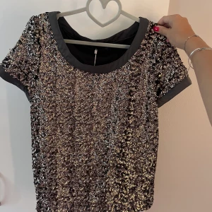 Cool T-shirt med paljetter -  topp med paljetter på framsidan från soaked in luxury, storlek M, bra skick