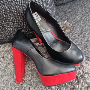 Nya högklackat  - Nya högklackade snygga svarta/röda aldrig andvända kostade 299:- blivit ett litet märke på som ni ser på bilden men inget som stör 