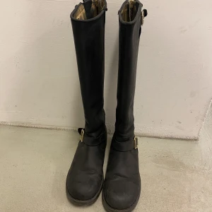 Svarta bikerboots - Svarta höga bikerboots i läder med gulddetaljer. Från märket Johnny Bulls. Köparen står för frakt🚚🥰