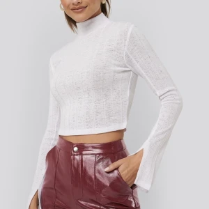 Vit croppad genomskinlig topp med hög hals - Vit topp från NA-KD x AFJ storlek XS. Tröjan är oanvänd och i bra skick. Den är croppad och genomskinlig. Halsen är mellan hög och ärmarna är vida. 