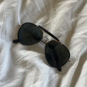 Solglasögon med läderdetaljer på bågarna 