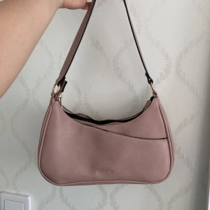 Söt rosa Axelväska - Helt oanvänd söt axelväska, köpt för nåt år sen, den är från dondonna. Priset kan diskuteras!