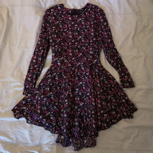 H&M klänning strl 34 - Svart blommig klänning från H&M, kjolen är typ v-formad med lite plissering vilket gör att den faller väldigt fint. Öppnas med dragkedja bak. Mått: 60cm i midjan, 78cm runt bysten, 84cm lång. Bilderna gör den inte rättvisa ärligt talat, den är så söt. 