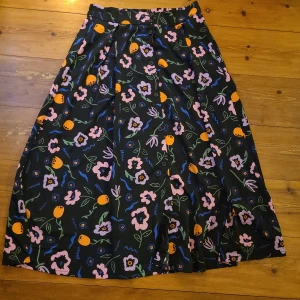 Kjol från MONKI - Fint begagnad kjol från Monki med härliga blommor. Knappar på framsidan. 