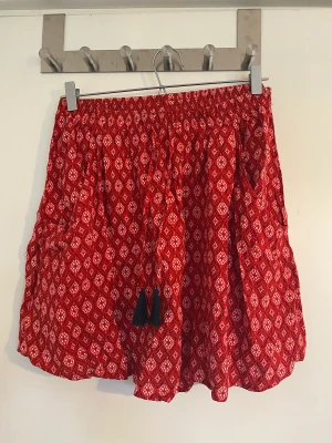 Röd flowig sommarkjol  - Kort kjol med blommigt mönster, knappt använd. 