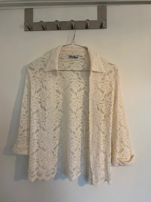 Spetsblus med blommigt mönster - Supervacker blus med krage och fina ärmar. Helt oanvänd.