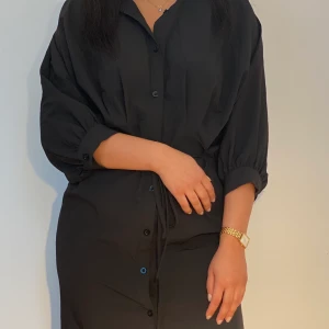 Klänning  - Knälång klänning med knappar och snöre man knyter rund midjan för att framhäva formen