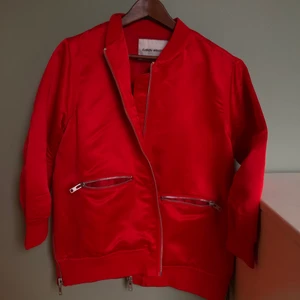 Carin Wester röd satin bomberjacka  - Säljer min fina röda ”bomberjacka” i satin. Märke CARIN WESTER. Storlek S. Den har massa fina detaljer som på sidorna där det är dragkedjor som matchar fickorna. Jackan är använd ett fåtal gånger, den är som ny. 