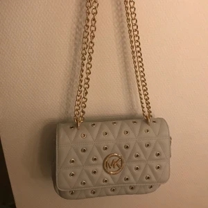 Handväska  - Aldrig använd så jättefint skick. Grå med gulddetaljer. Den är rymlig med flera fack 