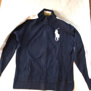 Ralph Lauren Zip Cardigan Strl L/14-16 Navy - En fin Ralph Lauren Vintage Zip Cardigan i Strl L/14-16 Navy/mörkblå. Använd till och från, bra skick men något utnött på materialets utsida. Utöver det är den välvårdad. Nypris: 900kr