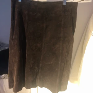 Äkta moccakjol - som ny - Säljer en supersnygg moccakjol i mellanbrun färg, svagt utsvängd, går ned till knäet, blixtlås bak