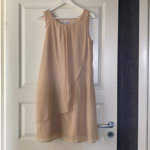 En ljus beige klänning stl38. Knappt använd. Tunt fint tyg 100% polyester tvättas i 30 grader.  Dragkedja i sidan.