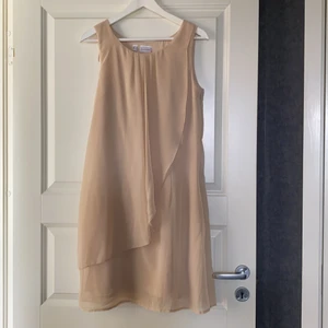 Klänning - En ljus beige klänning stl38. Knappt använd. Tunt fint tyg 100% polyester tvättas i 30 grader.  Dragkedja i sidan.