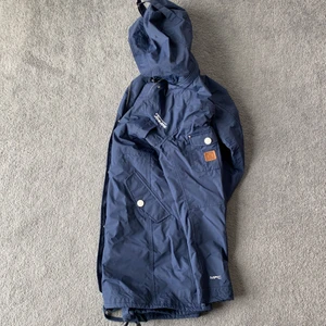 Tenson jacka marinblå stl 36 - ny - Helt oanvänd jacka från Tenson. Vattenavvisande med många fickor och dragsko i midjan. Avtagbar luva. 