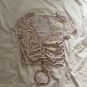 Topp - Mönstrad t-shirt som man kan knyta eller spänna vid magen, helt oanvänd så bra skick, buda i kommentarerna (start: 30kr+frakt) 