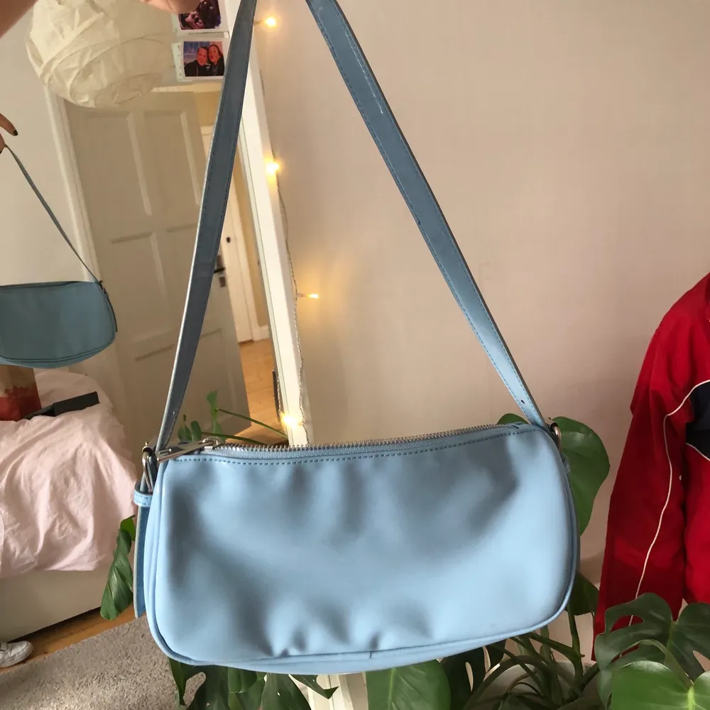 En babyblå vinyl baguettebag köpt från Nelly. Har en fläck (se bild 3)  som inte märks mycket alls om man inte kollar noga. Silvriga detaljer, dragkedja och har en ficka inuti. Skriv för fler bilder eller frågor!!!. Väskor.