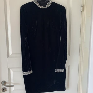 Klänning - Svart klänning i sammet, silvriga detaljer vid hals och ärmarna. Strl 38, säljs för 100kr. Frakt tillkommer! 
