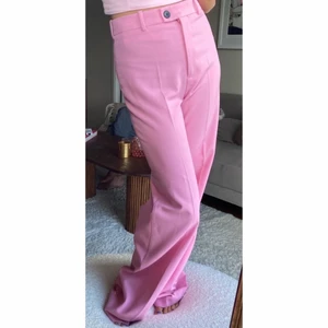 Rosa byxor med pressveck - Oanvända byxor med långa ben och hög midja. Pressveck fram och en dekorativ fick bak. Prislapp kvar. Ordinarie pris 549kr. Toppen på bilderna säljs också, se separat annons.