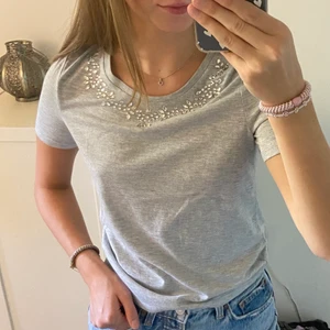 T-shirt - En grå t-shirt med jättefina stenar som detalj runt halsringningen. Helt ny med lappen kvar. Köparen står för frakten💕💕