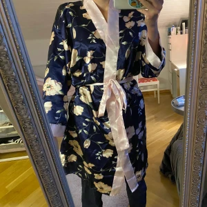 Morgonrock/kaftan - Säljer denna blommiga kaftan/morgonrock. Vet inte vilket material, men känns som silke/satin eller va det heter. Väldigt skön. Använd men i bra skick, se bild 3 så är bandet lite slitet men tror det är det enda.