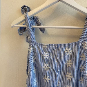 Klänning med brodyr - Klänning med broderade blommor. Från Asos. Storlek 34. Öppen rygg och axelband som man knyter.