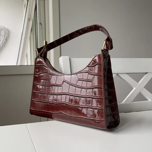 Brun axelväska  - Brun väska med guldkedja och gulddetaljer. Ca 25x17x6cm 