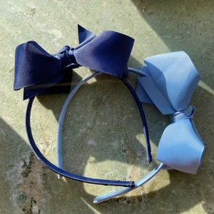 Hårskenor med rosetter - Otroligt söta hårband med rosett från butiken Lucca i Stockholm. En i mörkblå och en i ljusblå färg. Mycket bra skick och sitter inte för hårt på huvudet. Ett hårband 30kr och båda för 50kr