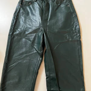 Gröna skinbyxor - Gröna skinbyxor från Pull and bear. Använda fåtal gånger, säljer för att det ej kommer till användning. Litet hål vid ena hylsan. Strlk 34. Frakt ingår ej i priset