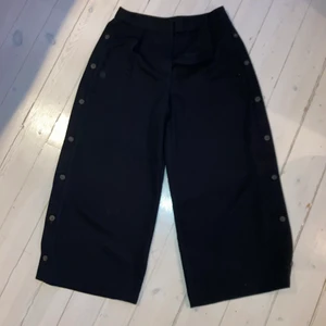 Vida byxor  - Vida vad-långa byxor med öppningsbara knappar utmed benen. Inget stretchigt material