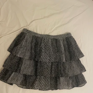Mönstrad svartvit kjol HM - En trendig volang kjol i svartvitt mönster, blandat prickar och leopard! Säljes pågrund av att den är lite stor!