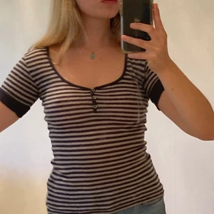 Randig topp från Acne - Jättesöt randig acnetopp! Smickrande djup ringning och med små knappar vid bröstet. Möts upp i Malmö eller fraktar!