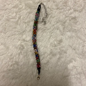 Handgjord armband  - Den här fina armband är gjord på glaspärlor. Olika färgglada pärlor. Den är ca 10 cm lång utan kedjan medräknat. 