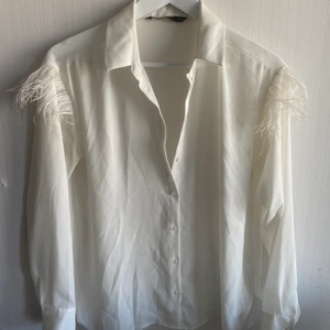 Skjorta från Zara - Tunn skjorta från Zara med fjäderdetaljer på axel. Använd fåtal gånger! Köparen står för eventuell frakt💕