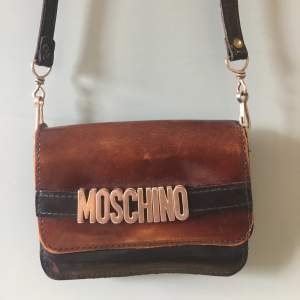 Vintage väska från märket moschino som behöver lite kärlek! (Se bild) Kan langa mått vid intresse samt fler bilder, men den e  mini! 