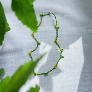 Pärlhalsband ”Gul sommarblomster” - GUL SOMMARBLOMSTER är ett pärlhalsband som är ca 40cm långt. Den har en karbinhake som håller smycket ihop.