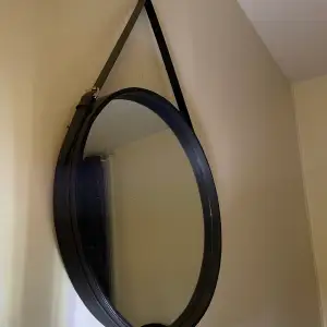 En rund spegel med ett läderband runt om spegeln. Går att justera med spännen. Spegeln säjs eftersom den inte används. Den är ca 50cm i diameter, det är okänt vart den är ifrån då jag fick den i julklapp. 