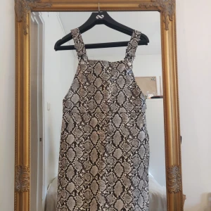 Linn Ahlborg x NA-KD klänning med hängslen - En hängsleklänning från Linn Ahlborg x NA-KD kollektionen som är helt ny. Säljer då den ej kom till användning 🥰 Storlek S material PU läder. Säljs på hemsidan för 250kr! 