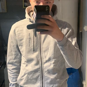 Grå Sail Racing zip hoodie - En grå Sail Racing zip hoodie som jag köpt från Kids Brand Store för ett år sedan. Tröjan sitter som storlek S elr M men den är för folk som är 170cm. Jag är lite mer än 170 och den sitter lite tajt på mig så den här storleken är bra om du är lite under 170cm. Pris går alltid att diskutera!