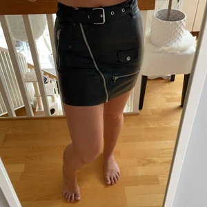 Svart kjol i fejkskinn i storlek XS - Kjolen är köpt i en affär i Frankrike tror jag, så den finna inte att köpa i Sverige. Den är otroligt fin att ha på fester men tyvärr är den för liten för mig. Kjolen har även jätte fina detaljer på hela framsidan med ett bälte som kan tas bort om man vill det. Köptes för 149kr