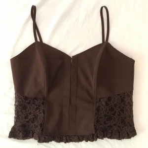 Brun korsett-topp - En skit snygg korsett-topp i brun färg och med spetsdetaljer, ryggen är helspets🤎 Lite liten över bysten för mig med ca F-kupa✨ Köpte i vintras och aldrig fått användning för tyvärr☀️ Storleken är uppskattad