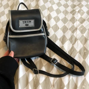 Liten ryggsäck  - Skitcool liten(20cm!) ryggsäck med justerbara band! Står tech sport på olika ställen. Fakeläder. I använt skick. 