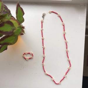 Handgjort pärlhalsband med matchande ring i rosa och rött med blommor i pärlemor. Halsbandet har standardspänne. Frakten ingår i priset <3