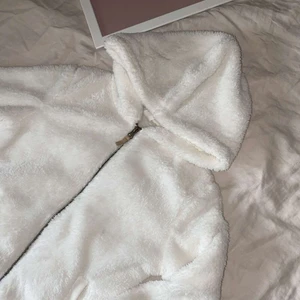 Mysig fluffig jacka/kofta - en fluffig vit hackande dragkedja, luva och fickor. Skönt om man fryser ibland:). Storlek 146/152. Skriv för mer frågor