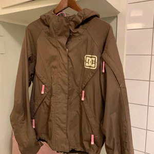 DCshoes skidjacka - Fin choklad/nougatbrun skidjacka med rosa detaljer. Världens bästa. Rymliga flickor för liftkort, vantar, mobil etc. Vindfickor och dragsko. Ursprungspris 5000kr. Finns inte i handel längre. 