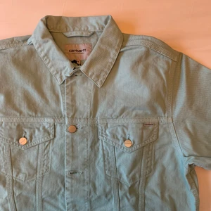Helt ny Carhartt Jeansjacka Strl M - Aldrig använt men den har en snygg färg och hög kvalitet. Passar som en vanlig jeansjacka och passar bra till vita byxor eller liknande.