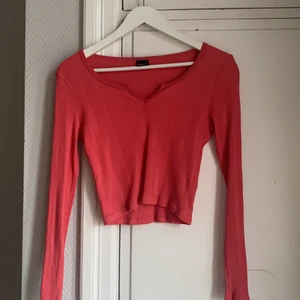 Tröja - Långärmad tröja med snygg detalj över brösten. Ser väldigt röd ut på bilderna men är mer åt de rosa hållet i verkligheten. Köparen står för frakten, spårbart. 